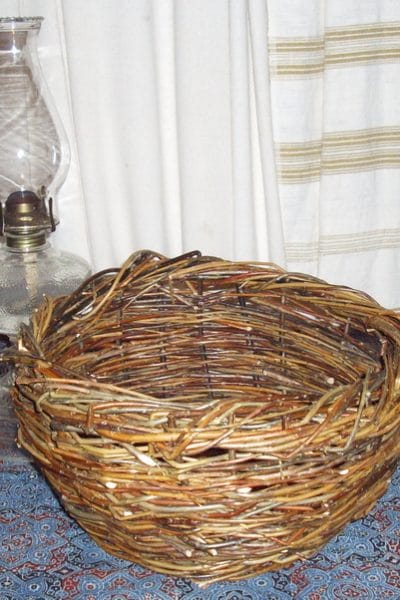 Hand woven willow basket sitting on a table beside an oil lamp