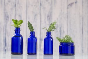 essential oil bottles with fresh herbs sticking out