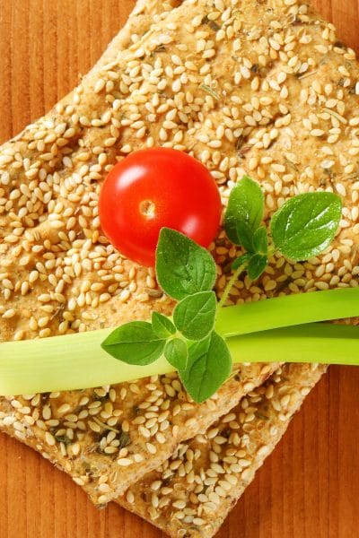 Sesame crackers stacked with a cherry tomato and celery on top