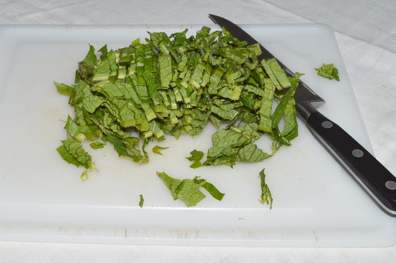 chopped comfrey leaves on a cutting board with a knife