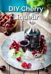 Cherry liqueur in a decanter and glass beside fresh cherries.