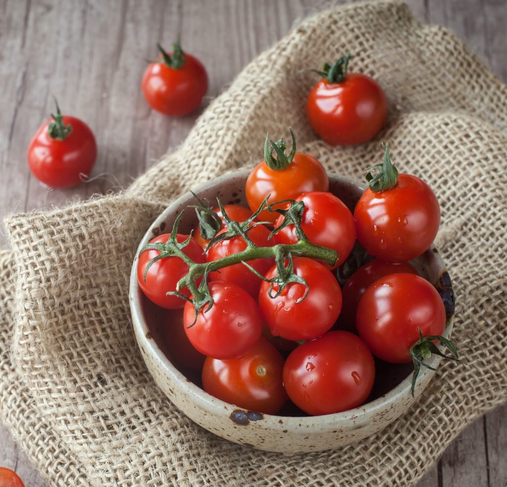 Fresh cherry tomatoes in a bowl on folded burlap
