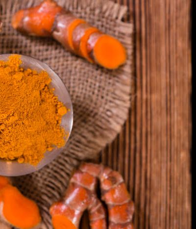 Fresh and powdered turmeric on a wooden background