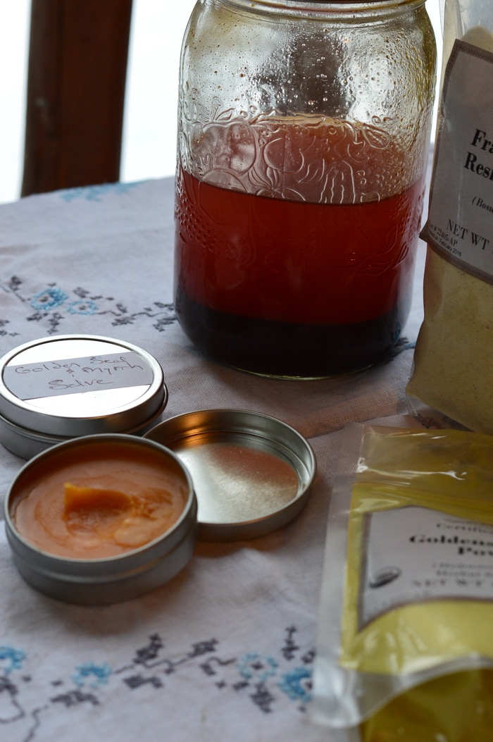 Ingredients for goldenseal, myrrh, and frankincense salve with finished salve in foreground.