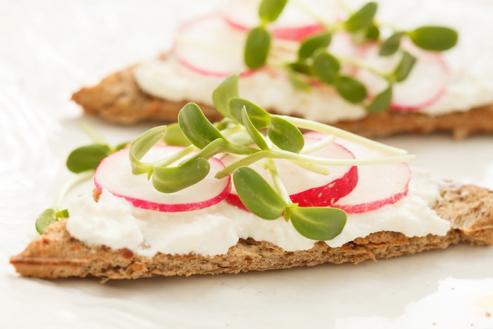 crackers with cream cheese, radish medalions, and sunflower sprouts
