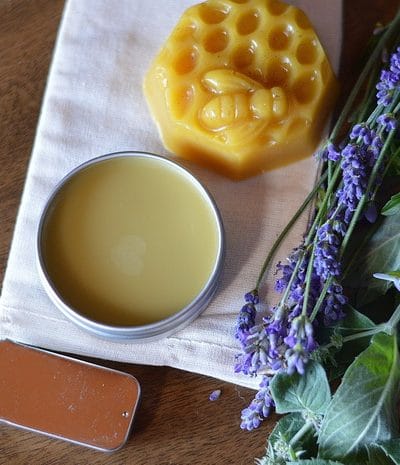 Salves sitting next to fresh lavender and other herbs