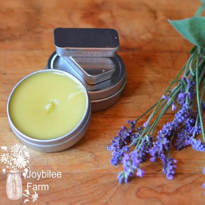 prepared salve on a wooden table with fresh lavender beside it, salve is a great way to apply essential oils for congestion